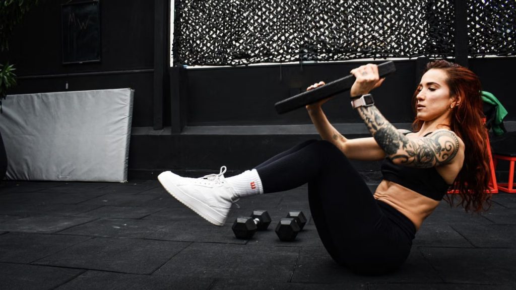 A determined woman performs a core workout in an indoor gym setting.
