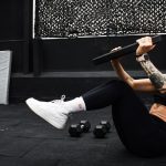 A determined woman performs a core workout in an indoor gym setting.