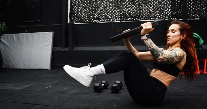 A determined woman performs a core workout in an indoor gym setting.